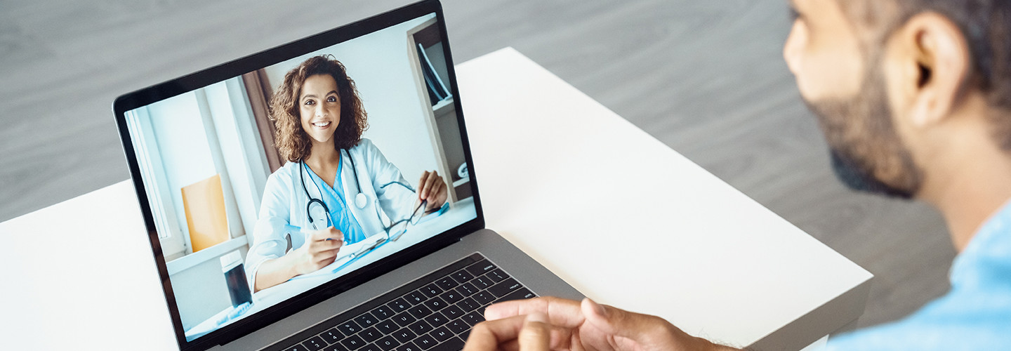 man attends telehealth appointment with doctor on laptop