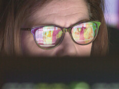 woman wearing glasses looking at healthcare data on screen